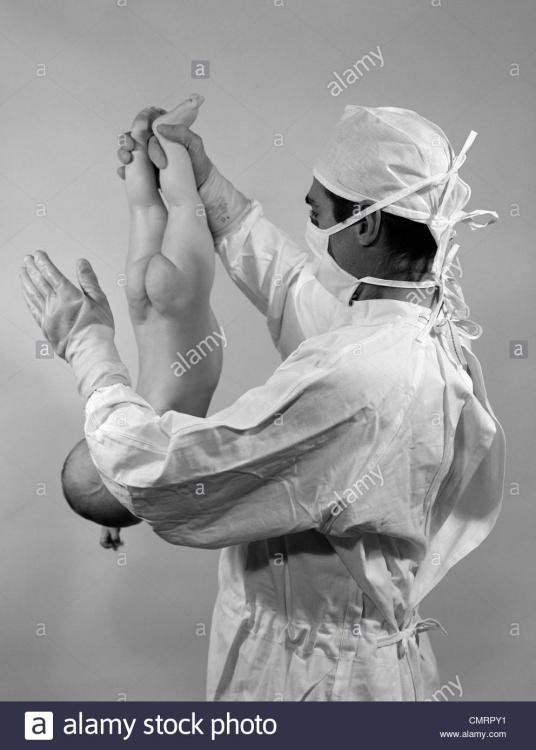 1960s-man-doctor-holding-newborn-baby-upside-down-by-ankles-slapping-CMRPY1.jpg